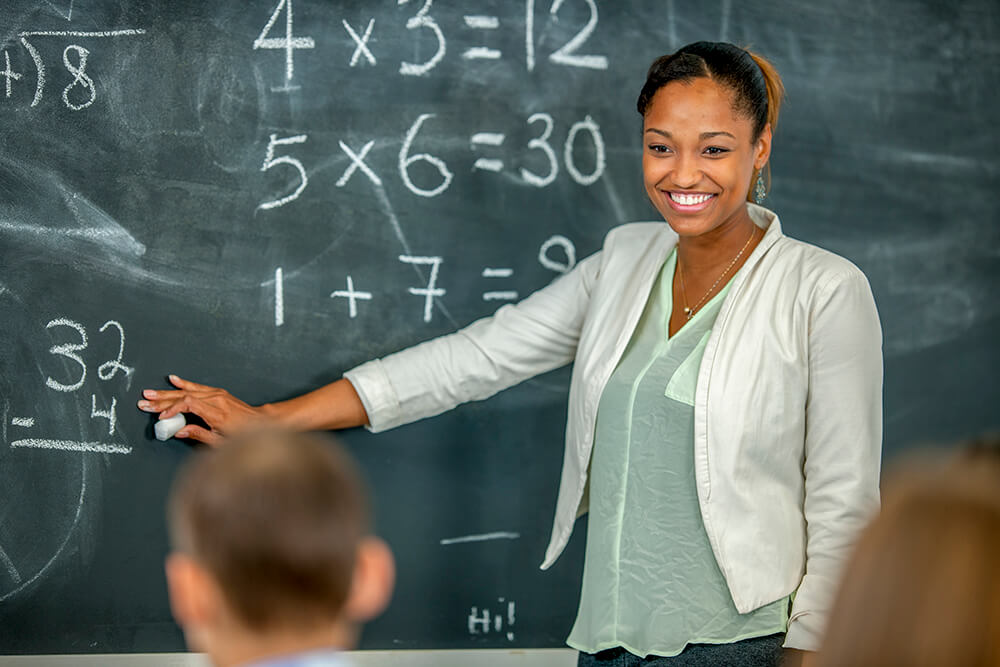 Woman teaching math to students, using a blackboard