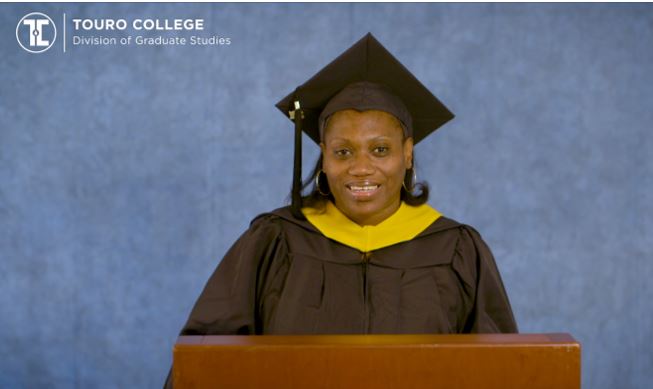 Tina Williams speaking at the virtual graduation ceremony. She is in cap & gown.